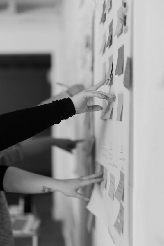 Hands arranging sticky notes on a black-and-white strategy wall